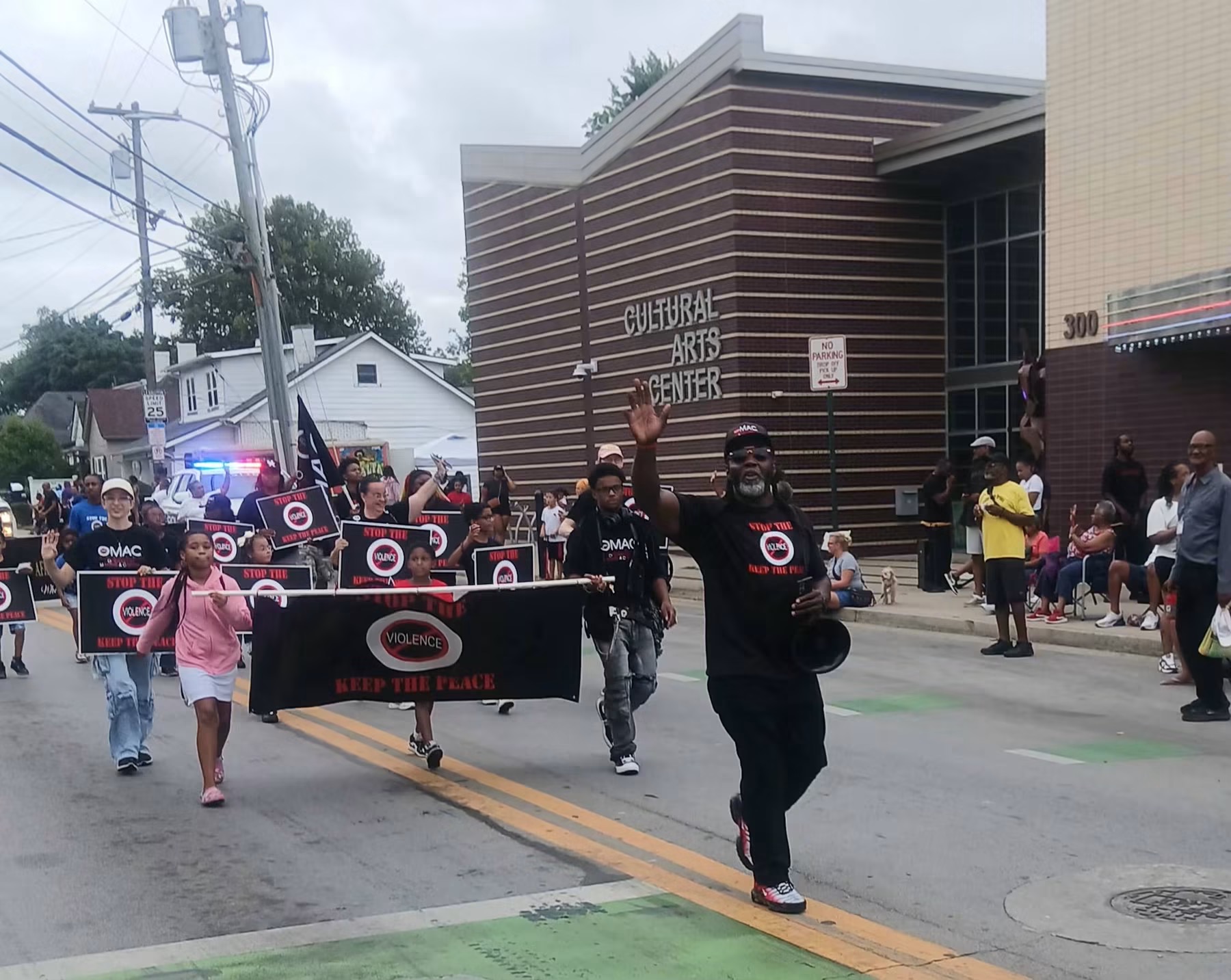 Community members marching with anti-violence signs during the Roots and Heritage parade outside the Historic Lyric Theatre