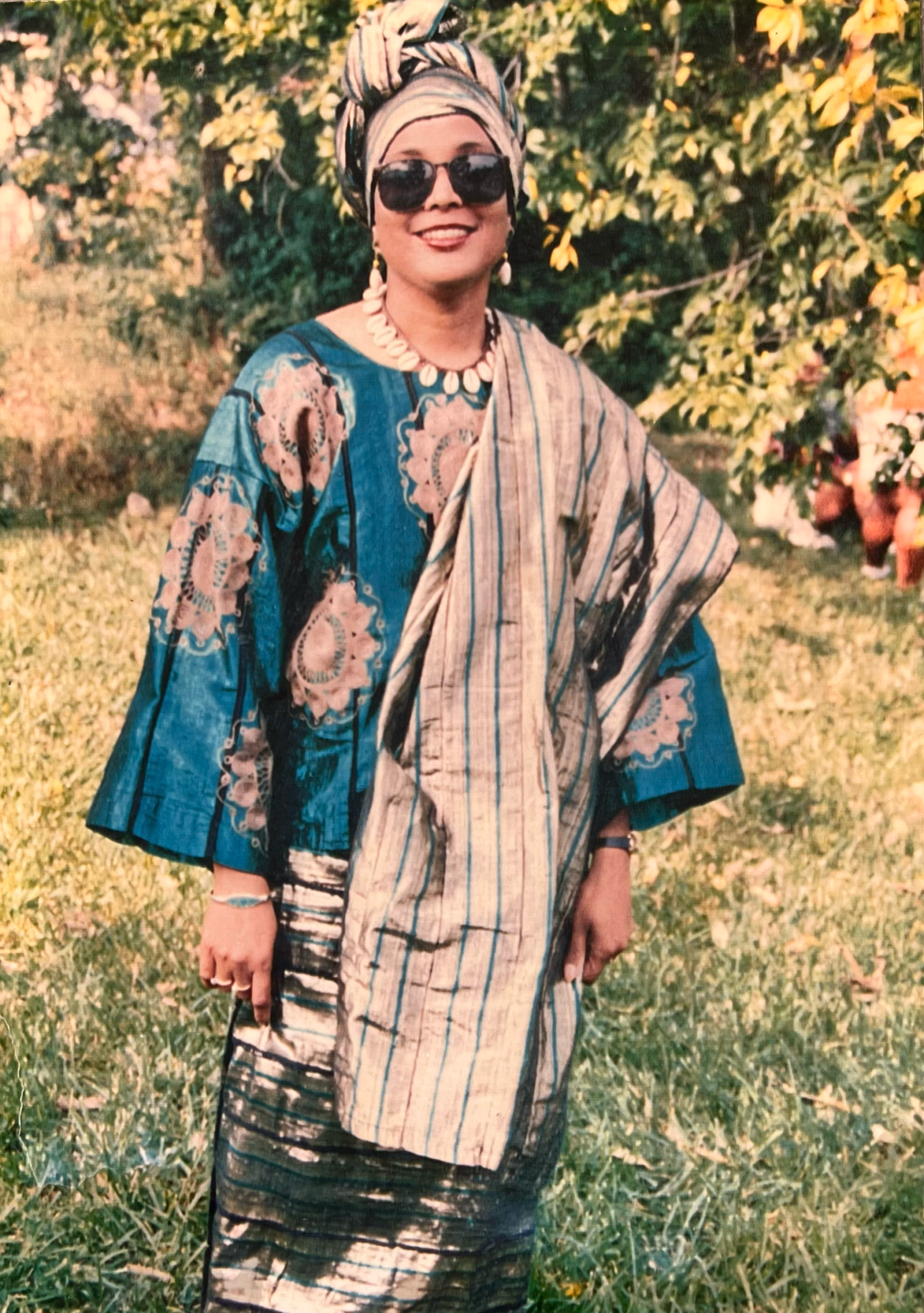 Catherine Warner standing outdoors in patterned clothing and a headwrap.